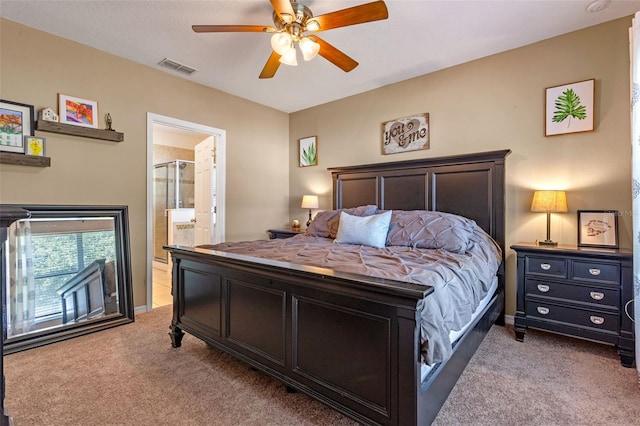 bedroom featuring light colored carpet, ceiling fan, and ensuite bath