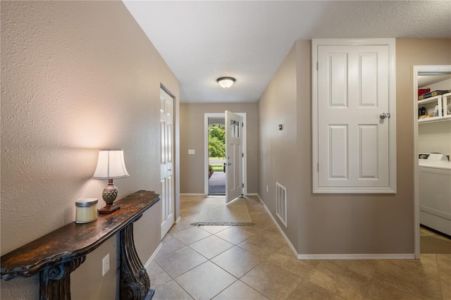 foyer entrance with washer / clothes dryer, baseboards, and light tile patterned floors