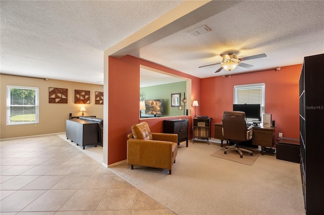 office space with a textured ceiling, a ceiling fan, light tile patterned flooring, light colored carpet, and baseboards