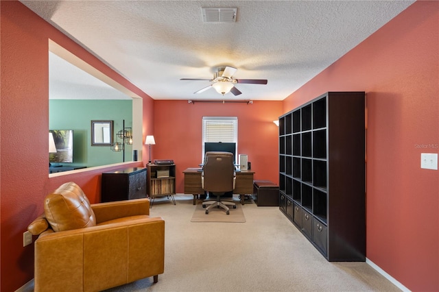 carpeted office with a ceiling fan and a textured ceiling