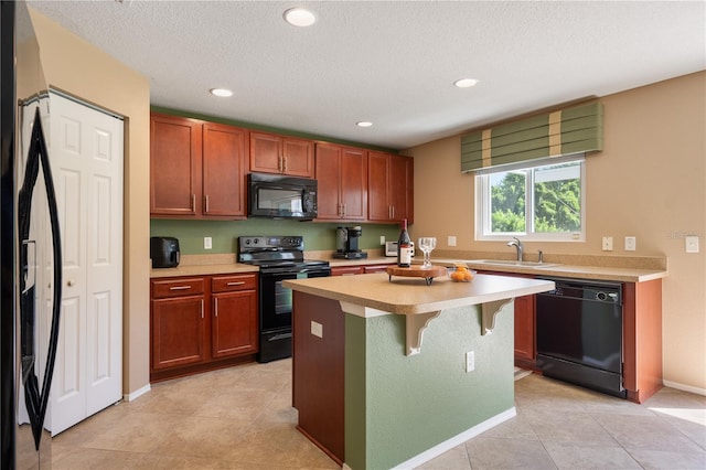 kitchen with black appliances, a sink, light countertops, recessed lighting, and a breakfast bar area