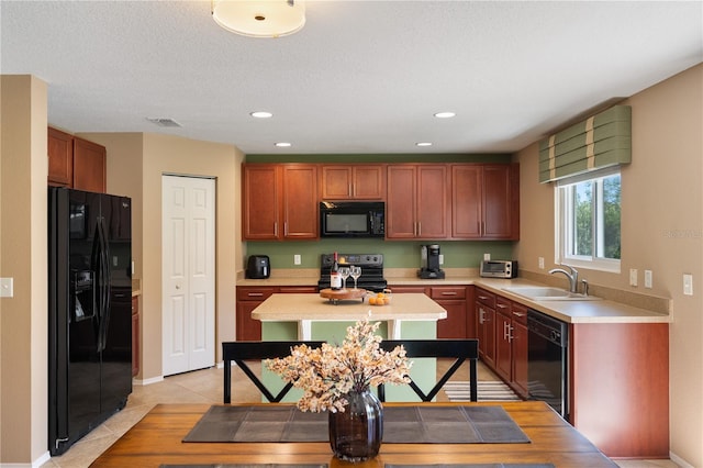 kitchen featuring black appliances, a sink, light countertops, light tile patterned flooring, and recessed lighting