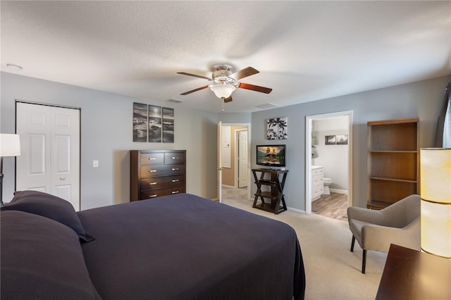 bedroom featuring light carpet, a closet, a ceiling fan, ensuite bathroom, and baseboards