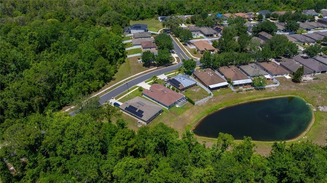 view of property location featuring a nearby body of water, nearby suburban area, and a forest