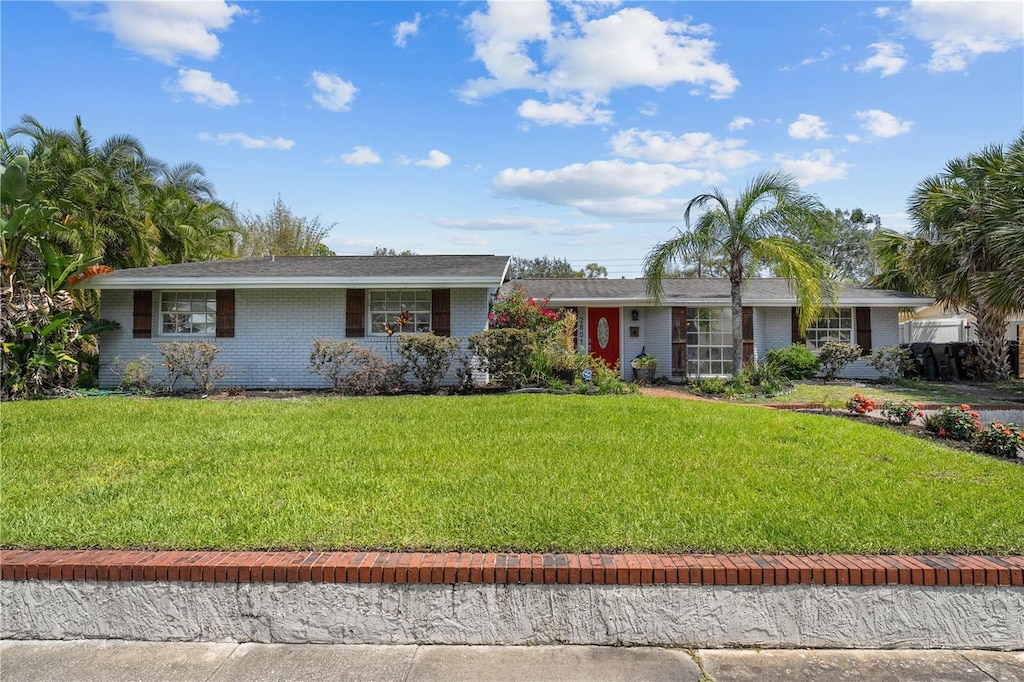 ranch-style house featuring brick siding and a front yard