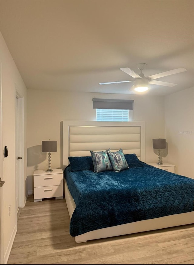 bedroom featuring light wood-style floors, a ceiling fan, and baseboards