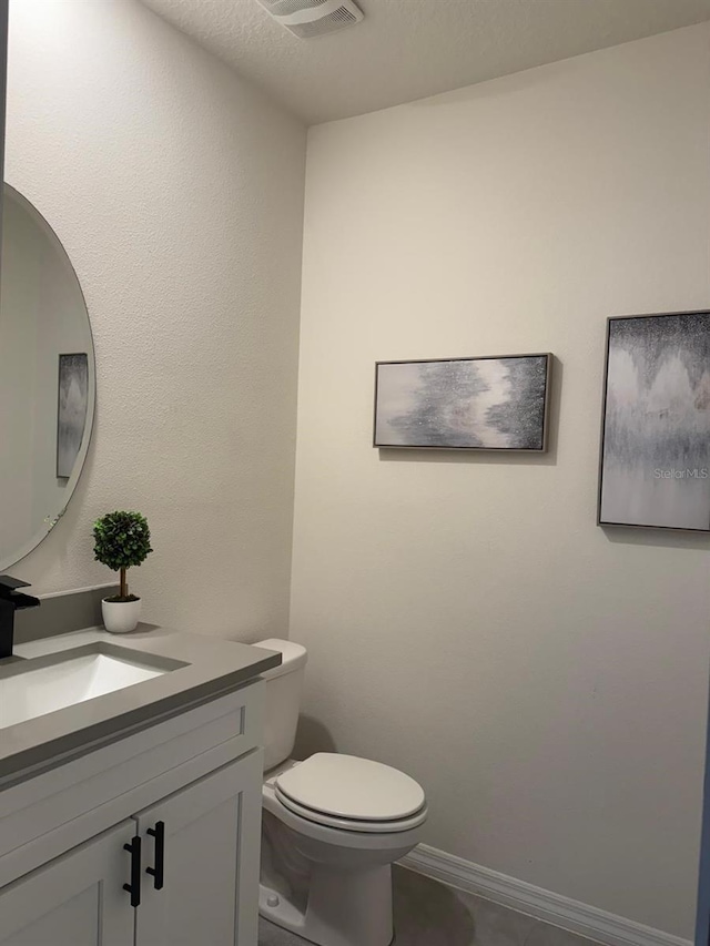 bathroom with vanity, toilet, and baseboards