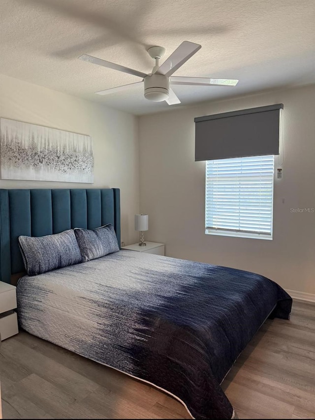 bedroom with wood finished floors, ceiling fan, and a textured ceiling