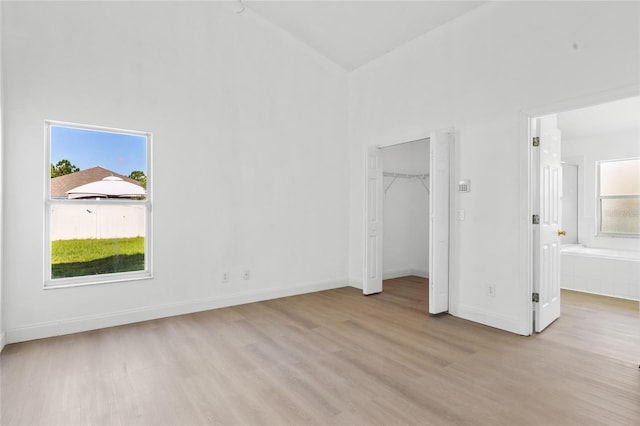 3078 Mandolin Dr, Kissimmee, FL 34744 - unfurnished bedroom with light wood-style flooring, high vaulted ceiling, baseboards, connected bathroom, and a walk in closet