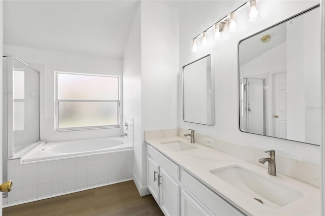 3078 Mandolin Dr, Kissimmee, FL 34744 - bathroom with a stall shower, wood finished floors, a garden tub, double vanity, and vaulted ceiling