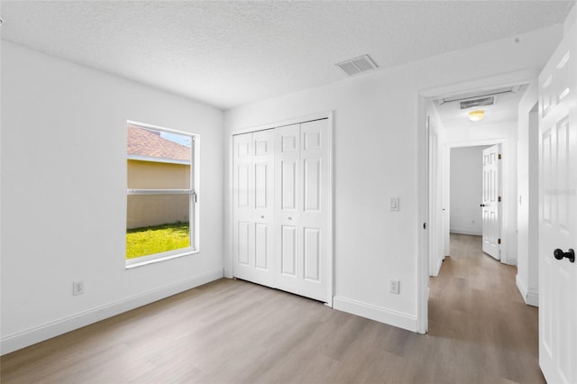 3078 Mandolin Dr, Kissimmee, FL 34744 - unfurnished bedroom with wood finished floors, multiple windows, baseboards, a closet, and a textured ceiling