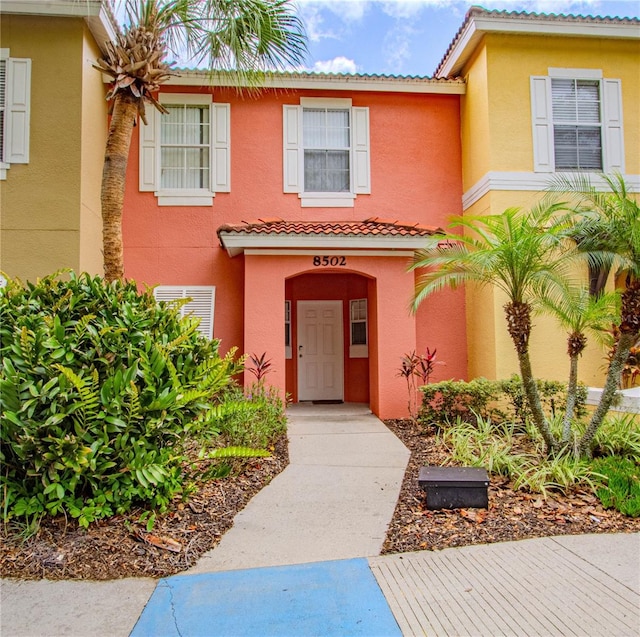 view of exterior entry with stucco siding and a tile roof