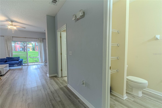 hallway with wood finished floors, baseboards, and a textured ceiling