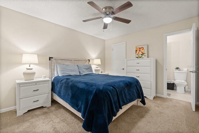 bedroom featuring light carpet, connected bathroom, a textured ceiling, baseboards, and a ceiling fan