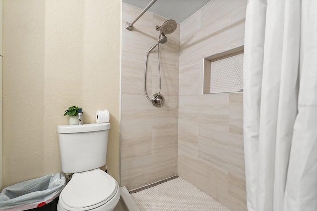 bathroom featuring a tile shower and toilet