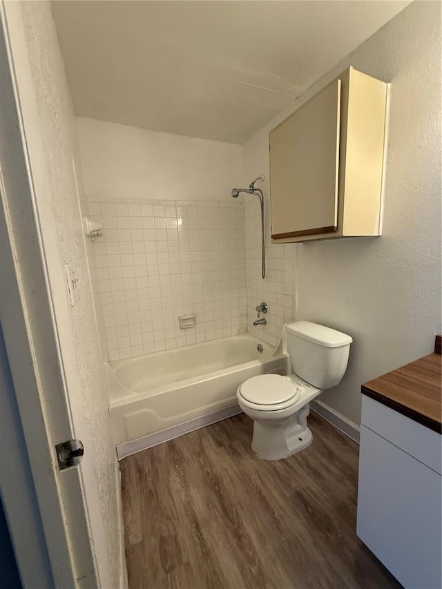 5540 Devonbriar Way Unit 103, Orlando, FL 32822 - bathroom featuring wood finished floors, a textured wall, toilet, washtub / shower combination, and vanity
