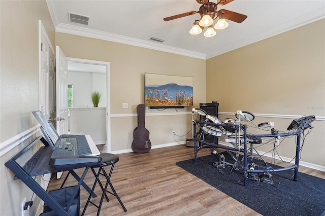 home office with wood finished floors, ornamental molding, a ceiling fan, and baseboards