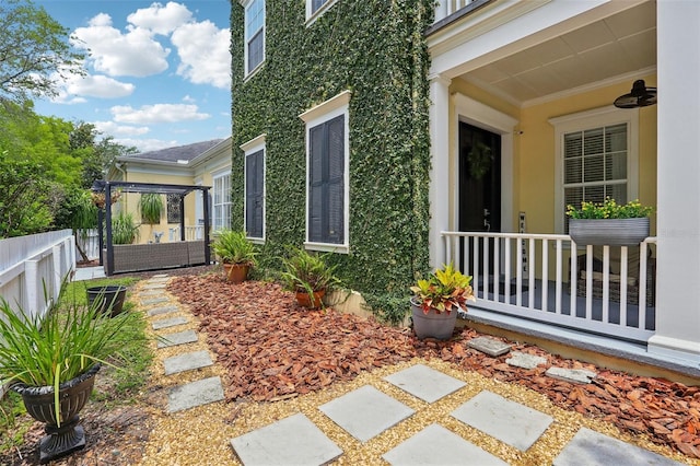 doorway to property featuring stucco siding and fence
