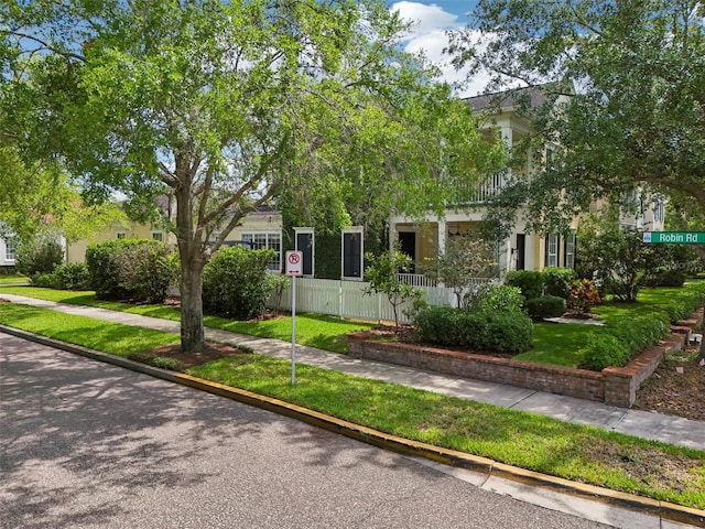 view of property hidden behind natural elements featuring a front lawn