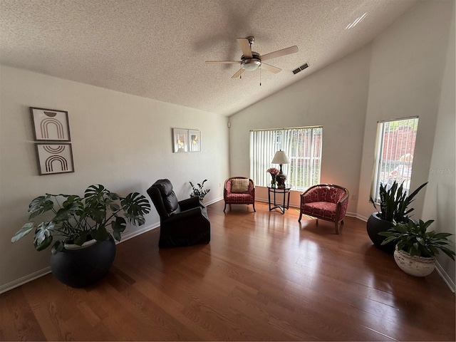 living area with a textured ceiling, ceiling fan, healthy amount of natural light, wood finished floors, and vaulted ceiling