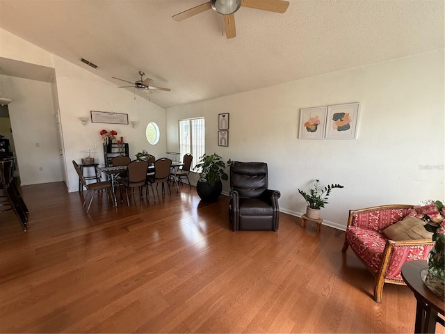 living area with a ceiling fan, wood finished floors, lofted ceiling, a textured ceiling, and baseboards
