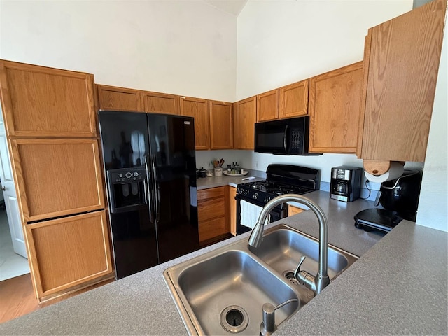kitchen featuring black appliances, a sink, a high ceiling, and brown cabinets