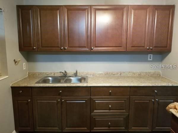 4061 Kirkland Blvd, Orlando, FL 32811 - kitchen with a sink, dark brown cabinets, and light stone counters