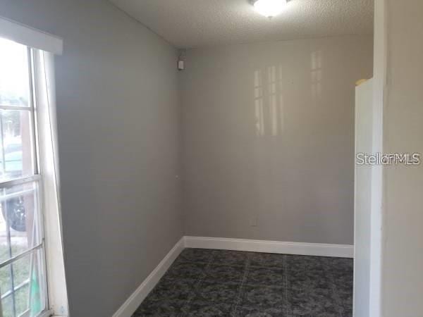 4061 Kirkland Blvd, Orlando, FL 32811 - empty room featuring healthy amount of natural light, baseboards, and a textured ceiling