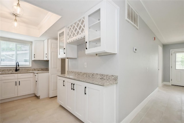 4651 Helena St NE, Saint Petersburg, FL 33703 - kitchen featuring a sink, white cabinets, light stone counters, glass insert cabinets, and a raised ceiling