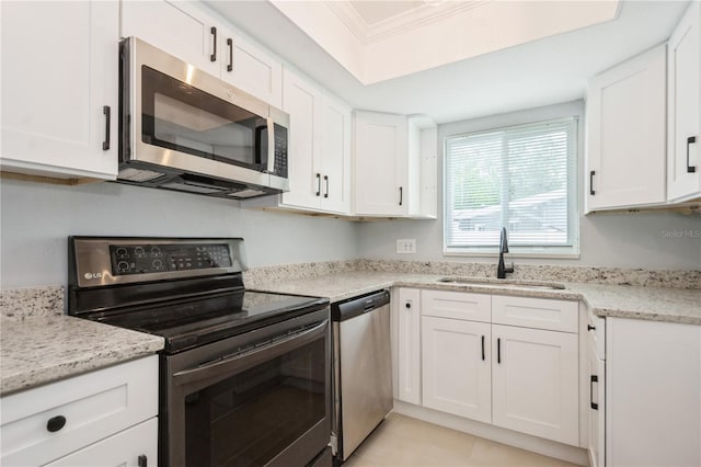 4651 Helena St NE, Saint Petersburg, FL 33703 - kitchen featuring stainless steel appliances, a sink, white cabinets, crown molding, and light stone counters