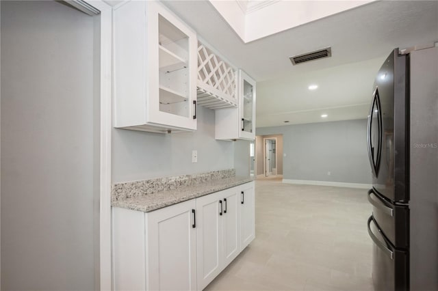 4651 Helena St NE, Saint Petersburg, FL 33703 - kitchen featuring freestanding refrigerator, white cabinets, glass insert cabinets, light stone countertops, and recessed lighting