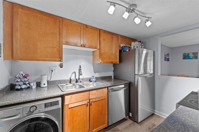 758 E Michigan St Unit 208, Orlando, FL 32806 - kitchen with washer / dryer, a sink, appliances with stainless steel finishes, light wood-style flooring, and brown cabinetry