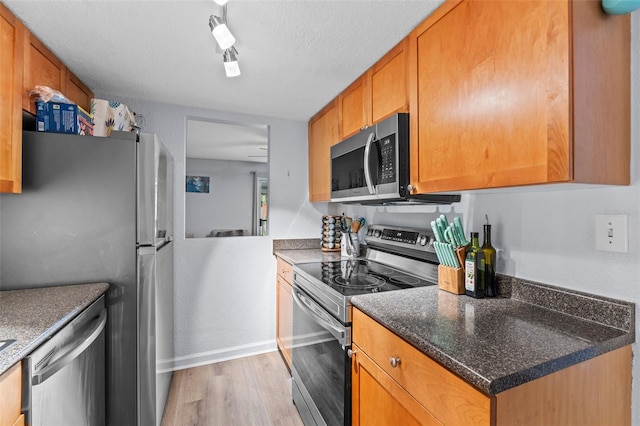 758 E Michigan St Unit 208, Orlando, FL 32806 - kitchen featuring appliances with stainless steel finishes, light wood-style flooring, baseboards, and brown cabinetry