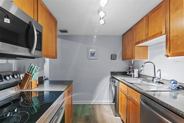758 E Michigan St Unit 208, Orlando, FL 32806 - kitchen with appliances with stainless steel finishes, a sink, washer / dryer, baseboards, and wood finished floors