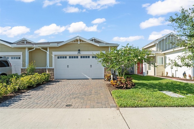 view of front of home featuring decorative driveway, an attached garage, stucco siding, a front lawn, and stone siding