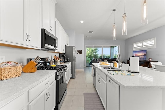 kitchen with stainless steel appliances, a sink, open floor plan, a kitchen island with sink, and white cabinetry