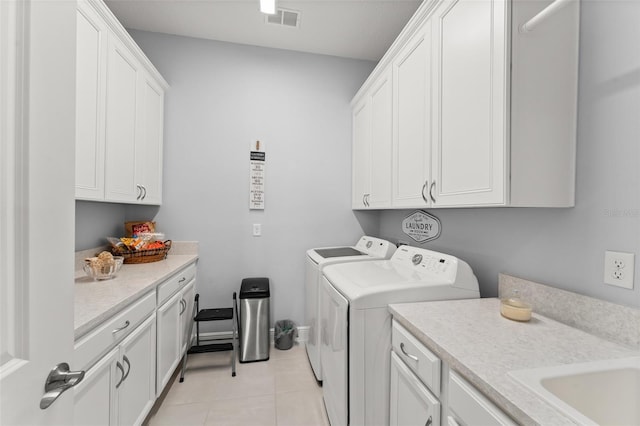 laundry room with cabinet space, washer and clothes dryer, and light tile patterned floors