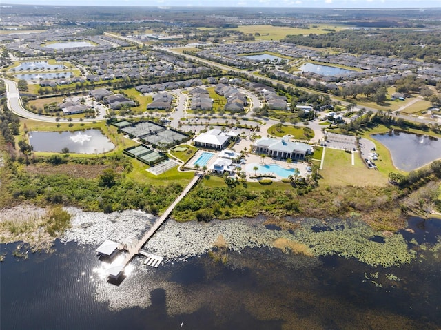 aerial view of property and surrounding area featuring a nearby body of water, a pool area, and nearby suburban area