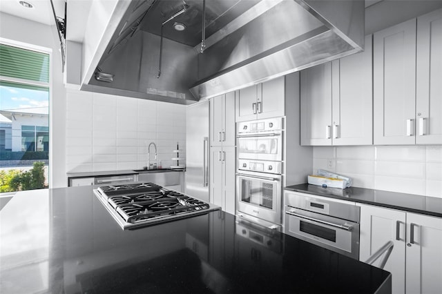 kitchen with a sink, appliances with stainless steel finishes, dark countertops, and backsplash