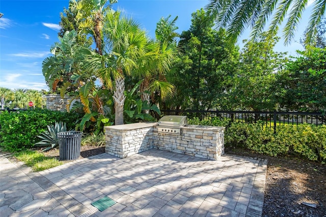 view of patio / terrace featuring exterior kitchen, fence, and a grill