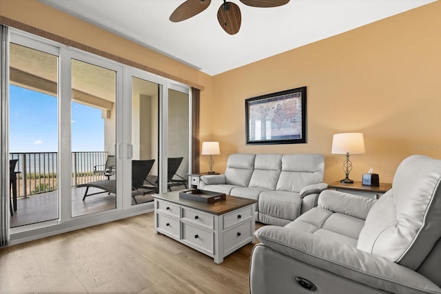 living area with light wood-style floors, ceiling fan, and a water view