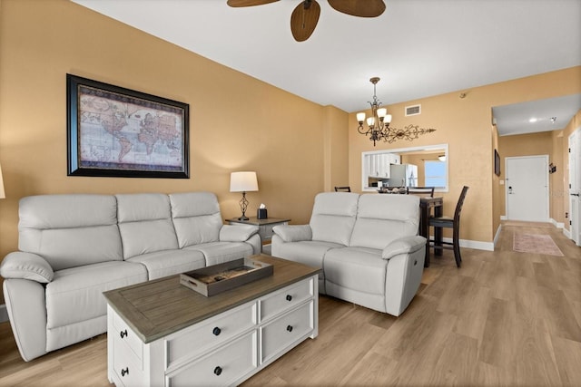 living area featuring a chandelier, light wood finished floors, ceiling fan, and baseboards