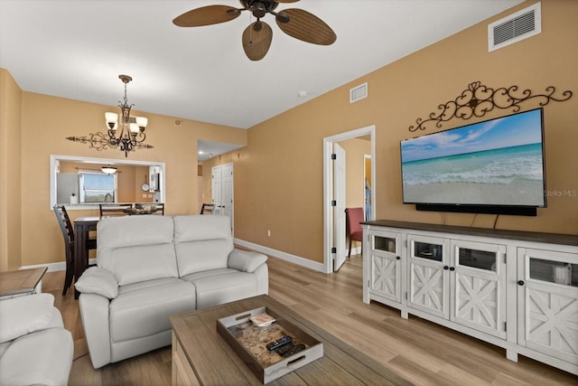 living room featuring ceiling fan, wood finished floors, a chandelier, and baseboards