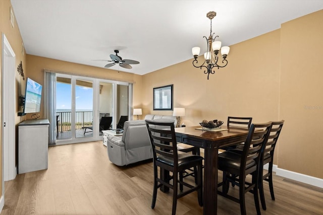 dining area with wood finished floors, a ceiling fan, a chandelier, and baseboards