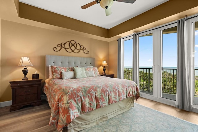bedroom with access to outside, a water view, wood finished floors, and ceiling fan
