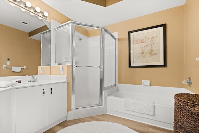 bathroom featuring a shower stall, a bath, vanity, and wood finished floors