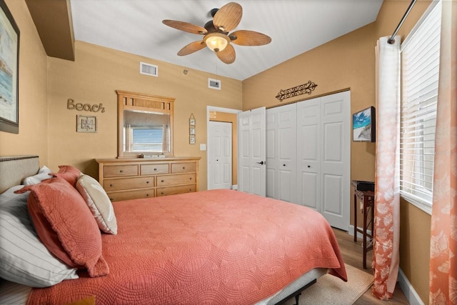 bedroom featuring wood finished floors, multiple windows, a closet, and a ceiling fan