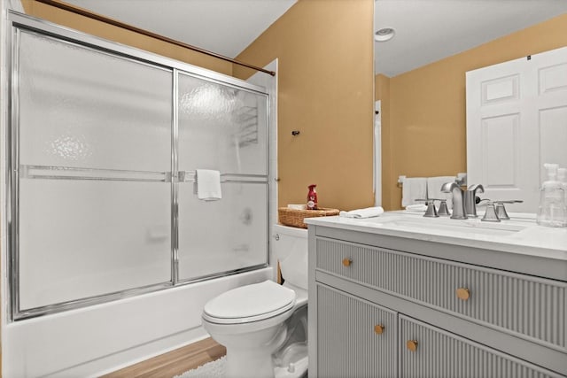 full bath featuring toilet, shower / bath combination with glass door, vanity, and wood finished floors