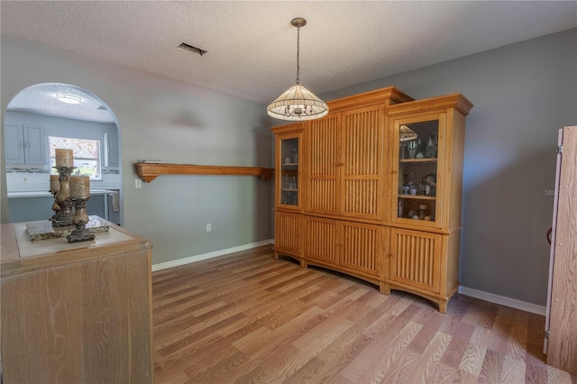 3216 White Blossom Ln, Clermont, FL 34711 - dining room featuring arched walkways, a textured ceiling, and light wood finished floors