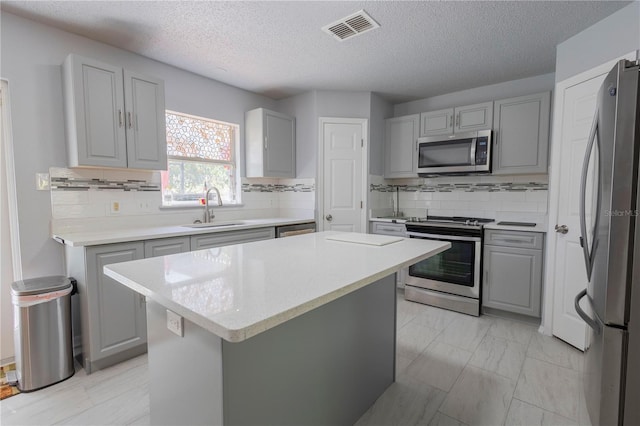 3216 White Blossom Ln, Clermont, FL 34711 - kitchen featuring stainless steel appliances, gray cabinetry, light marble finish flooring, a center island, and a textured ceiling